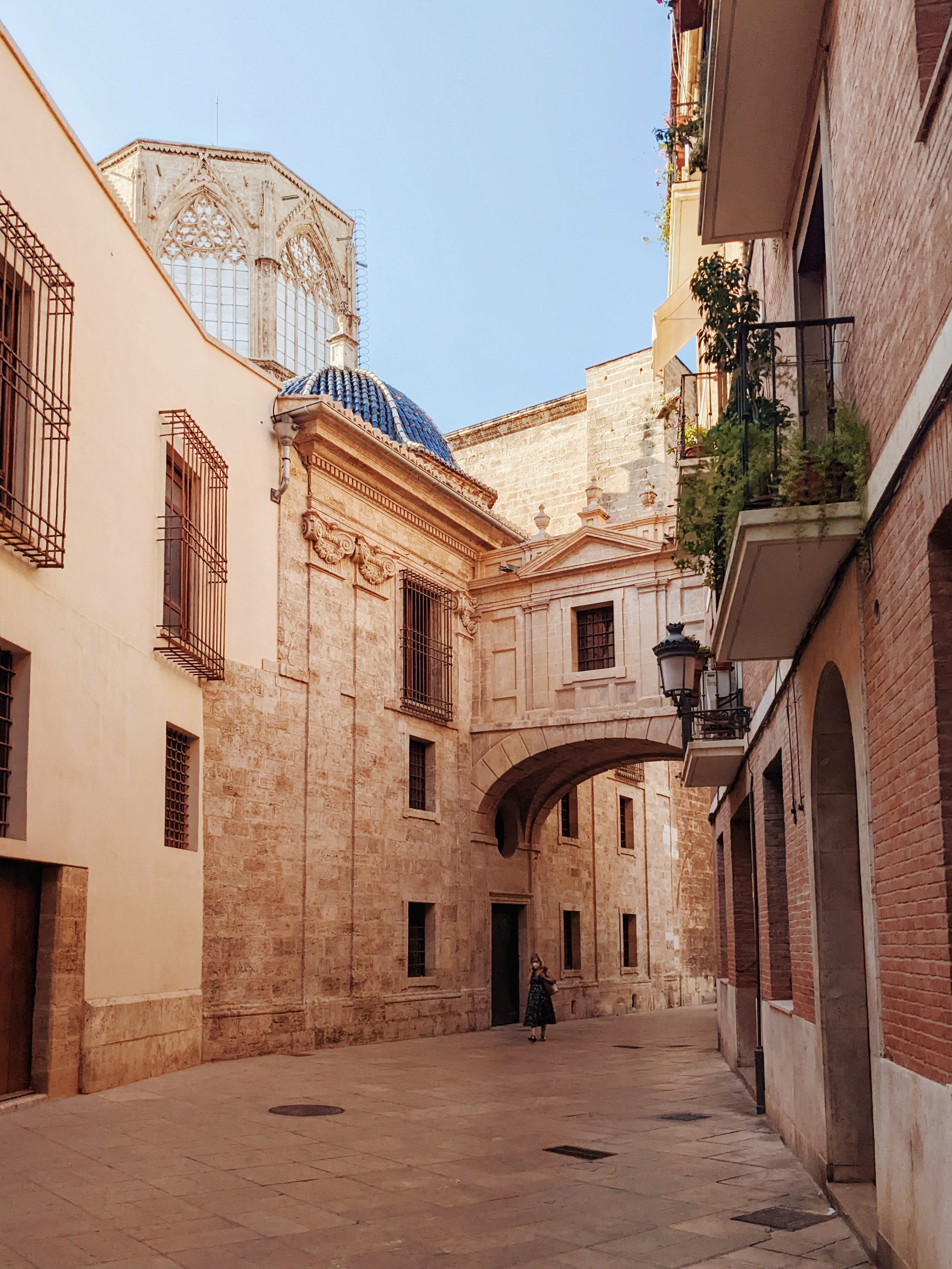 A woman walks under an archway in Old Town Valencia. July 2022