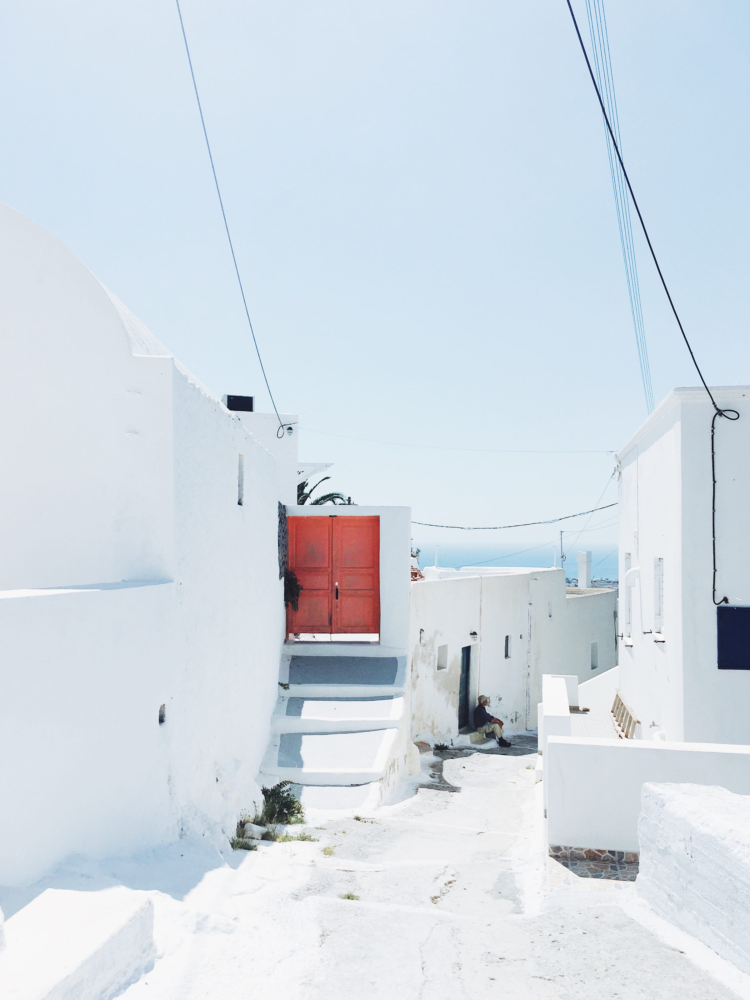 A local man sits in an alleyway leading down to the sea. Greece, 2017