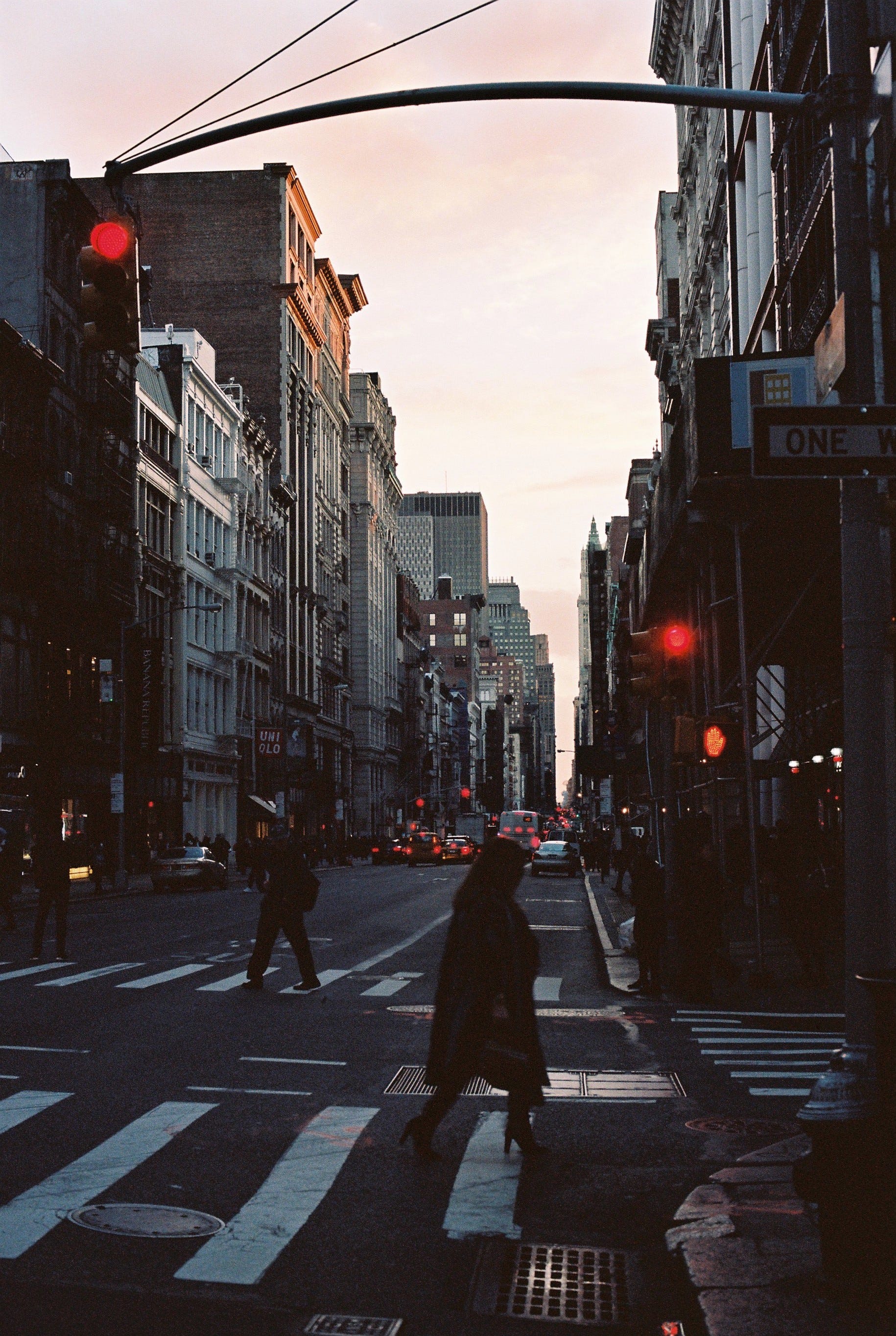 A woman in silhouette crosses a sunset-bathed street. New York 2018