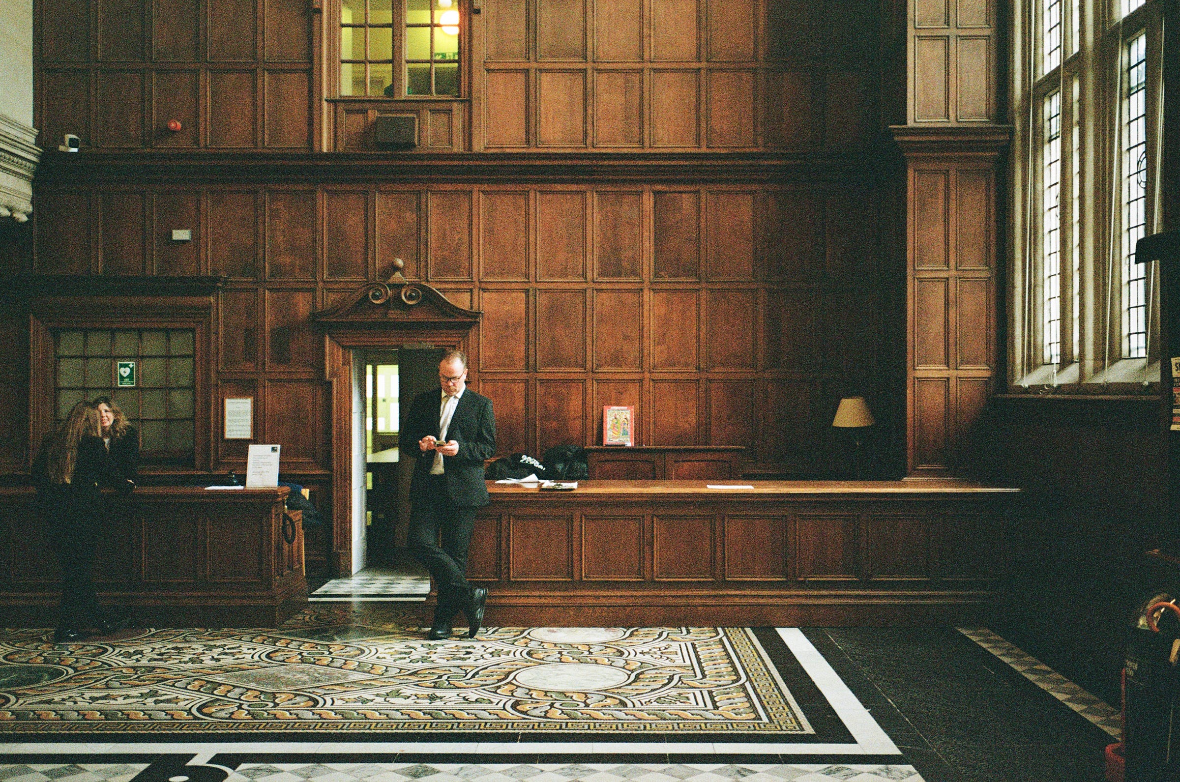 A man stands in front of a beautifully imposing wood wall. Oxford 2023