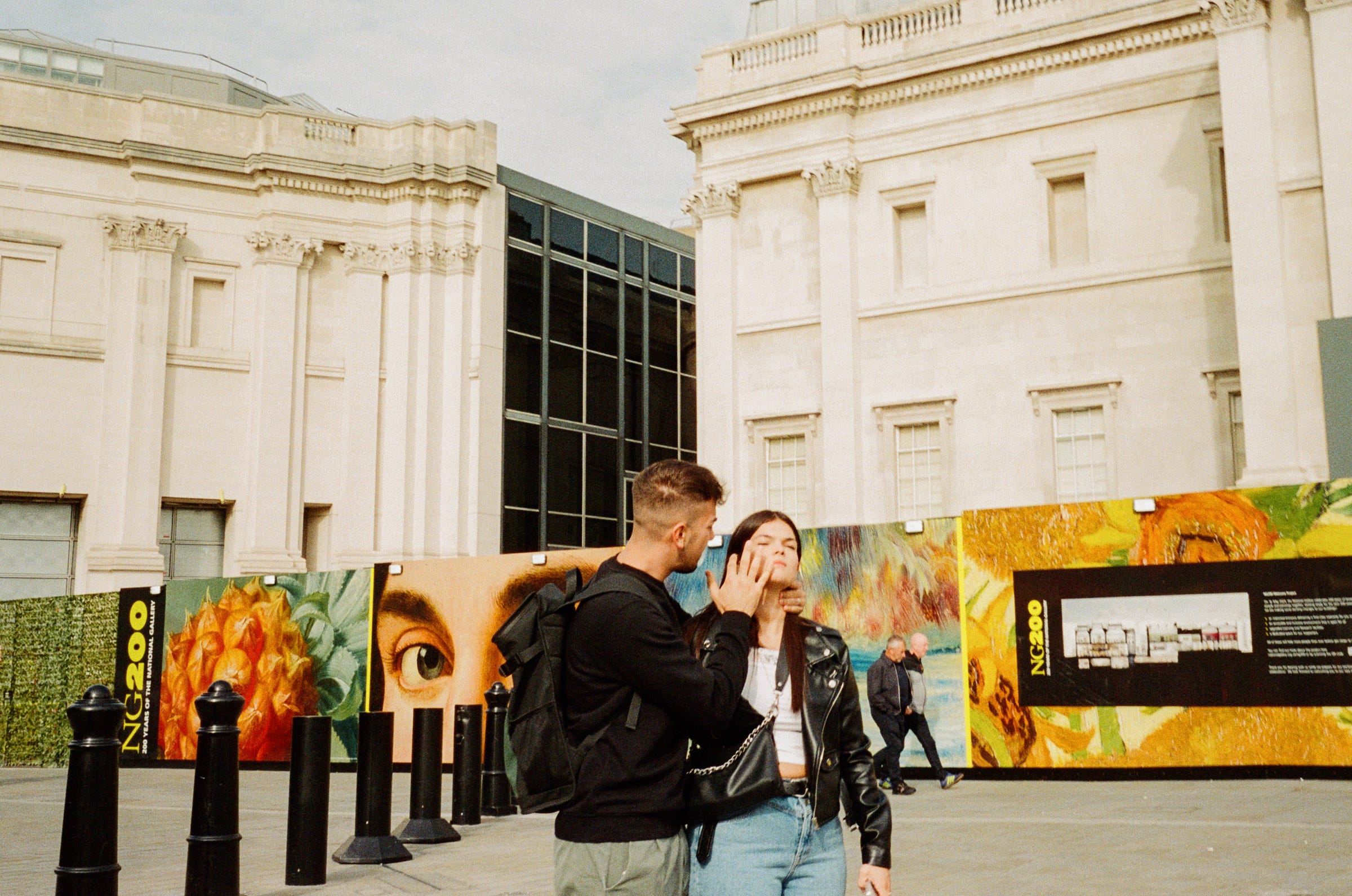 A girl gets looked after by a doting guy. A big eye stares on. London 2023