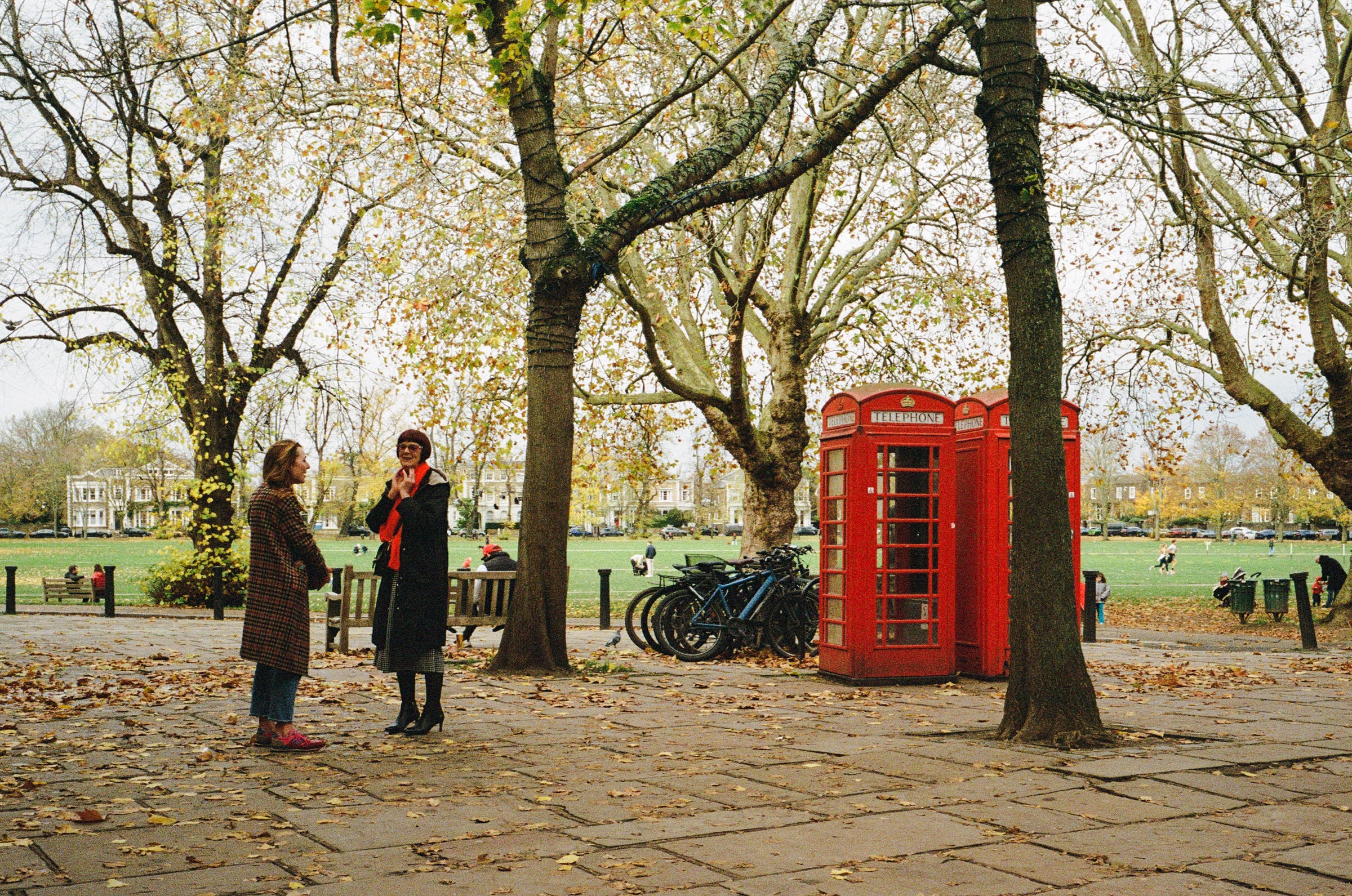 A woman with a red scarf matches the red phone booths nearby. London 2023